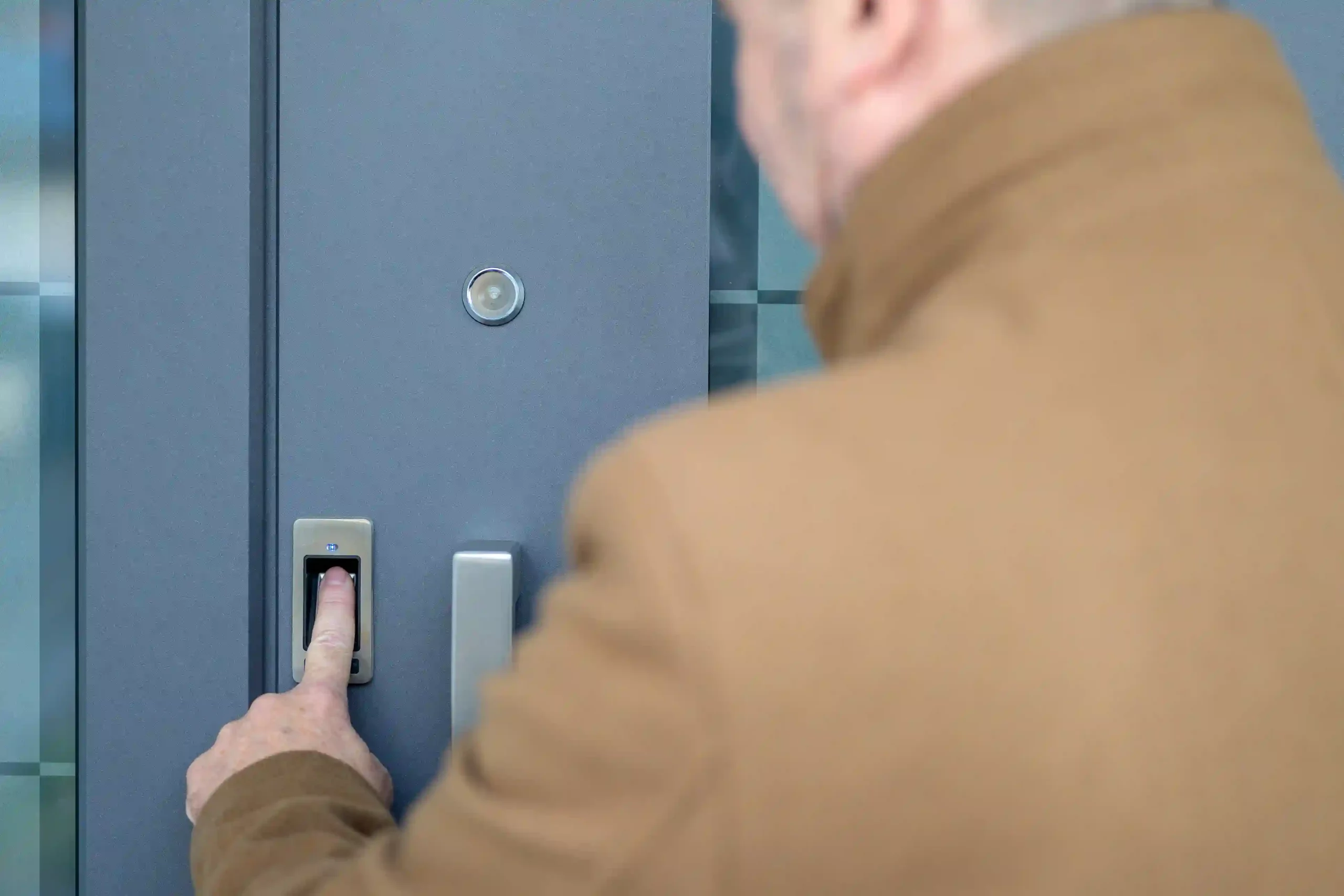 Persoon gebruikt vingerafdrukscanner op een moderne voordeur.