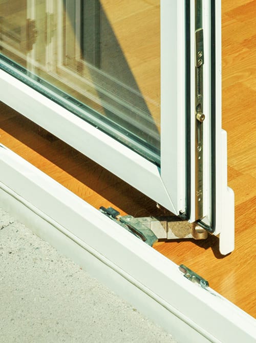 Detail van een witte schuifdeur met schienensysteem, geïntegreerd in een houten vloer.