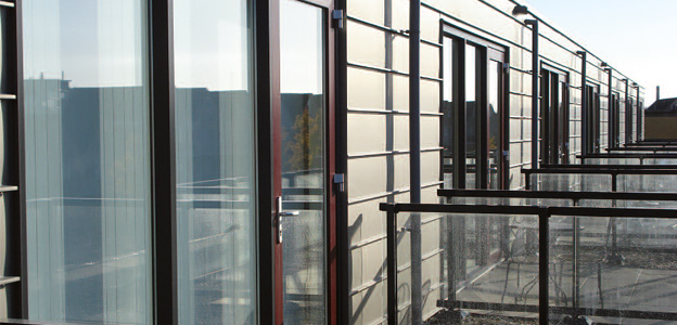 Moderne balkongevel met glazen ramen en balustrades in een rijtjeshuisstructuur bij daglicht.