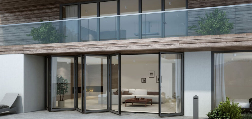 Modern gebouw met houten en witte gevels, glazen vouwwanden op de benedenverdieping en een glazen balkon met planten op de bovenverdieping. Binnen is een stijlvolle woonkamer zichtbaar.