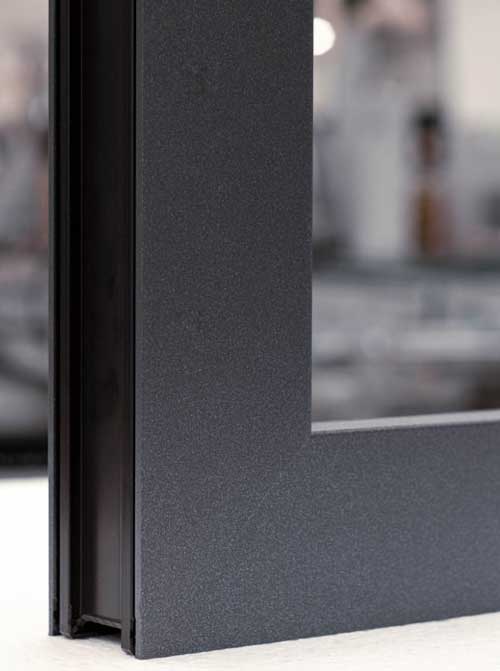 Close-up van een donkergrijs aluminium raamprofiel met een matte afwerking, tegen een onscherpe achtergrond.