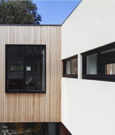 Een modern huis met een stijlvolle houten gevel en zwarte aluminiumramen.