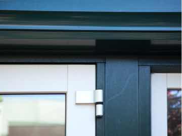 Detailopname van een witte dubbele vleugeldeur met een groen frame en een zilverkleurig scharnier.